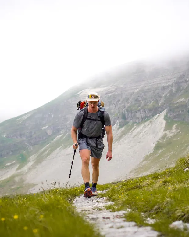 Jack climbing a stony mountain path under low cloud, pack and poles